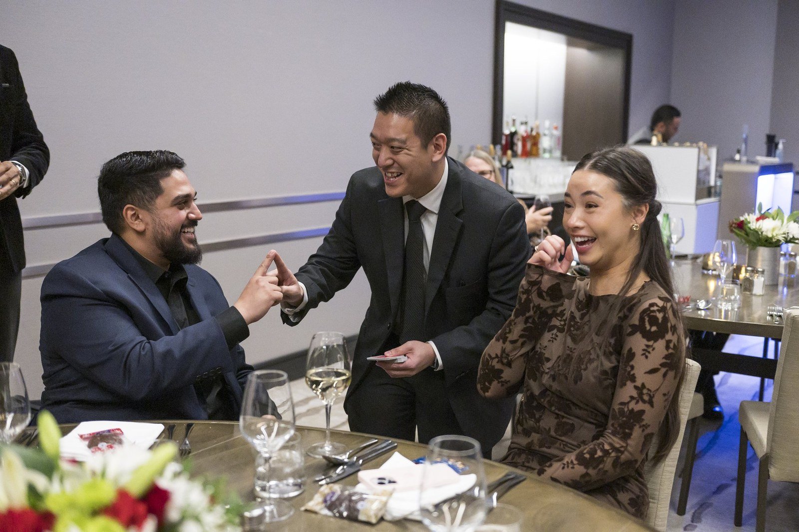 John Ha performing close-up magic for laughing guests during a Vancouver pre-dinner reception