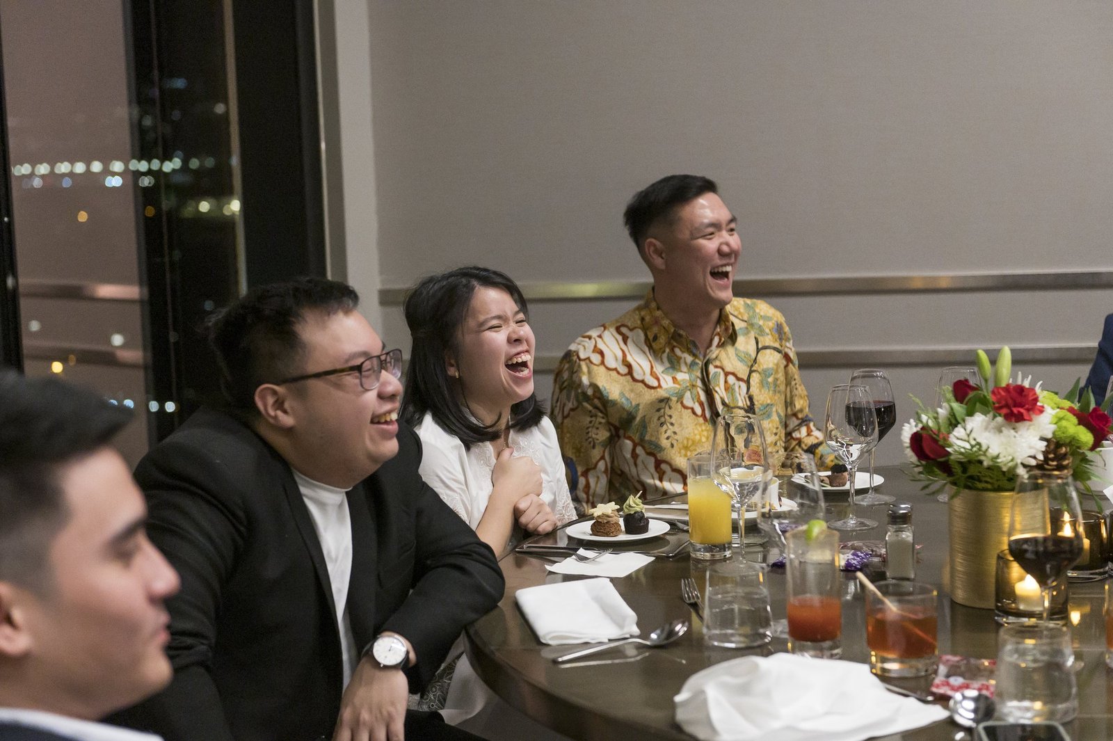 Dinner guests laughing during a John Ha close-up magic performance