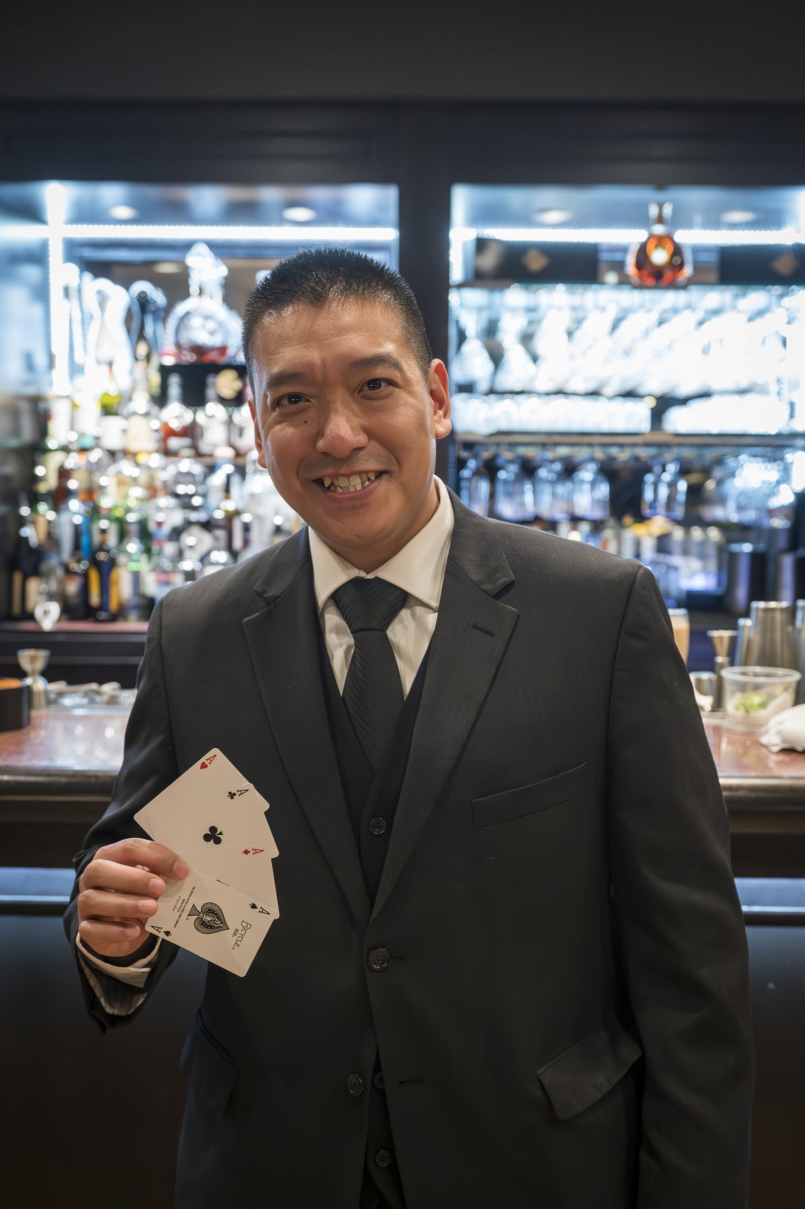 John Ha smiling at a bar while holding four aces