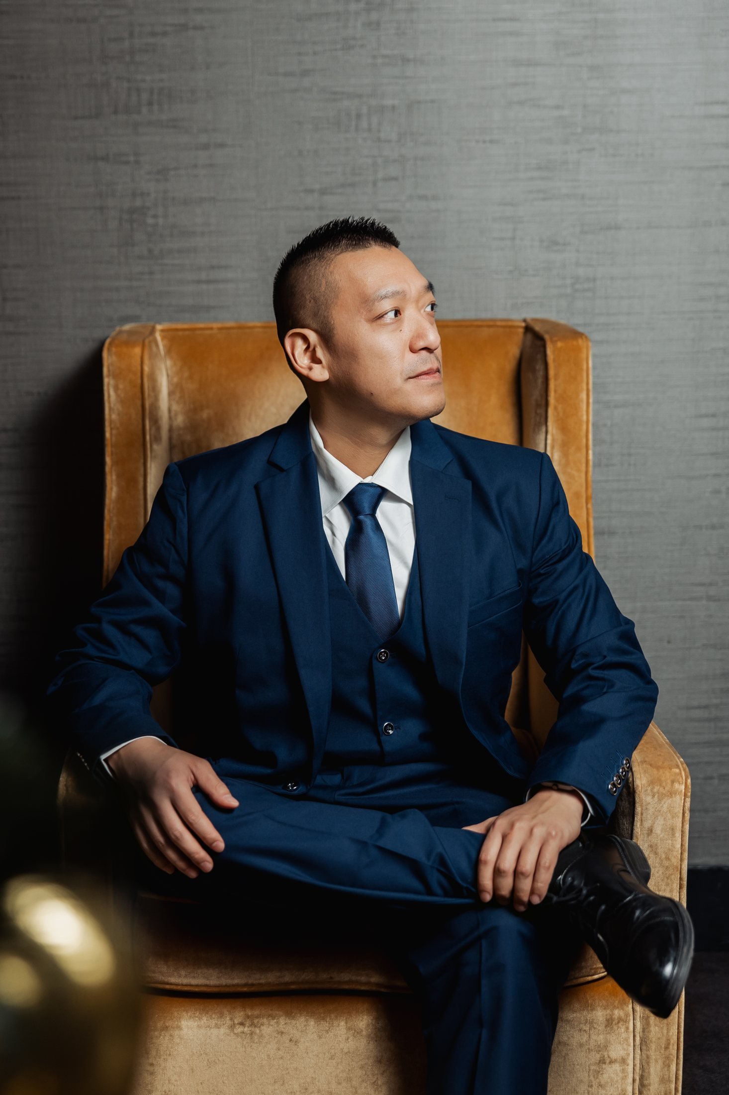 John Ha seated in a blue suit for a professional portrait